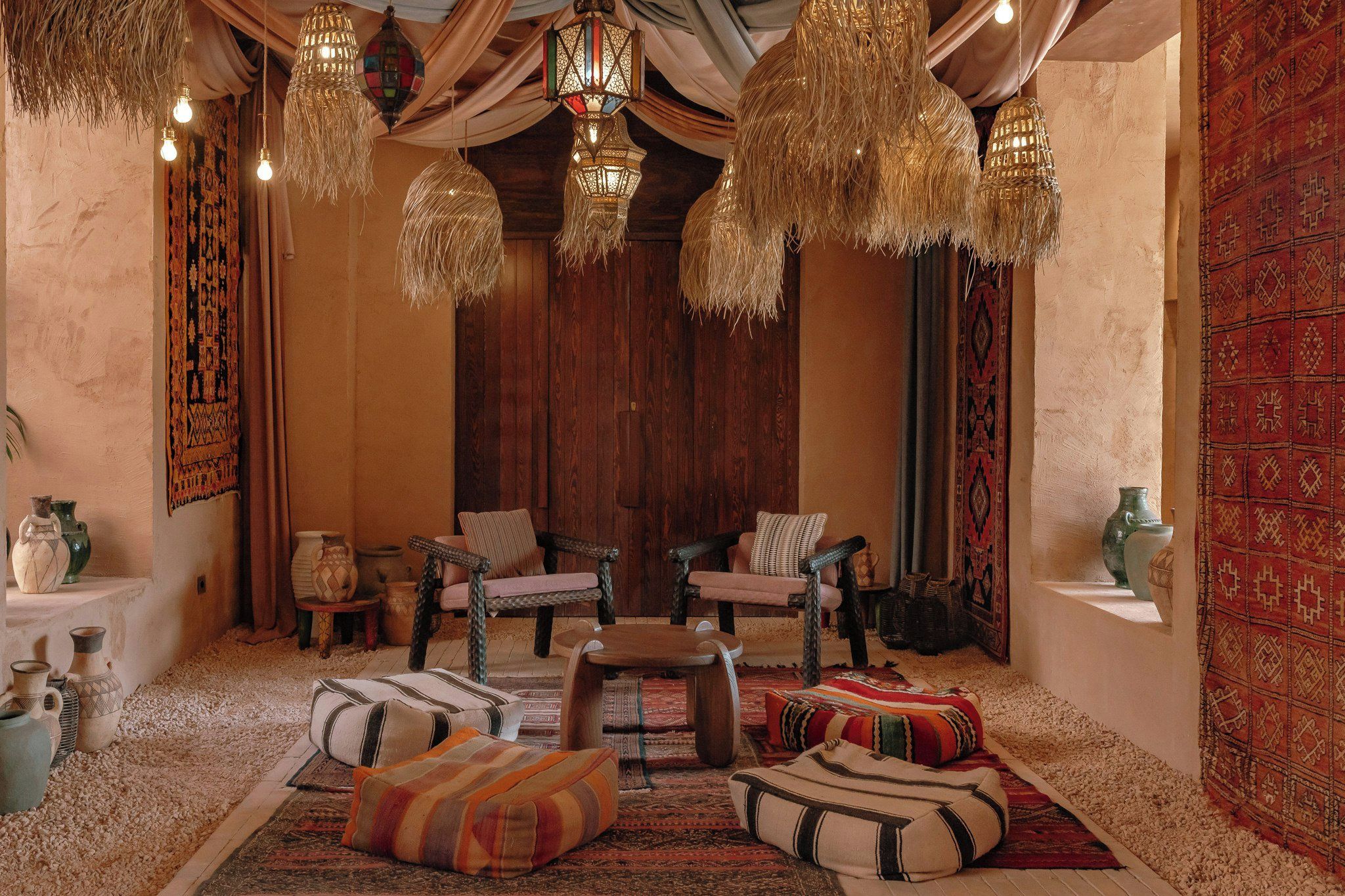 A cozy interior with wooden furniture, hanging lamps, and patterned textiles.