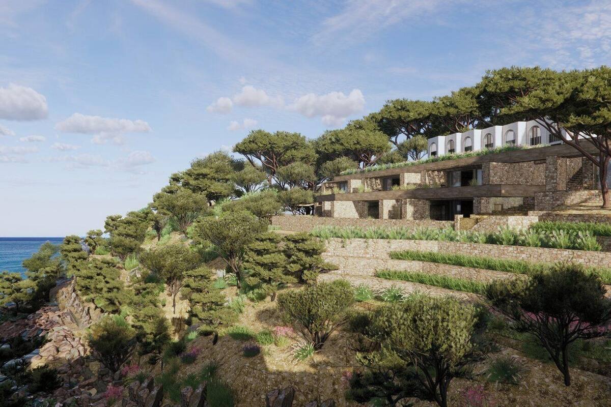 A coastal villa with a stone facade, terraced gardens, and a view of the sea.