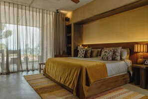 Un dormitorio con una cama grande, cabecera de madera y vistas al exterior a través de cortinas translúcidas.