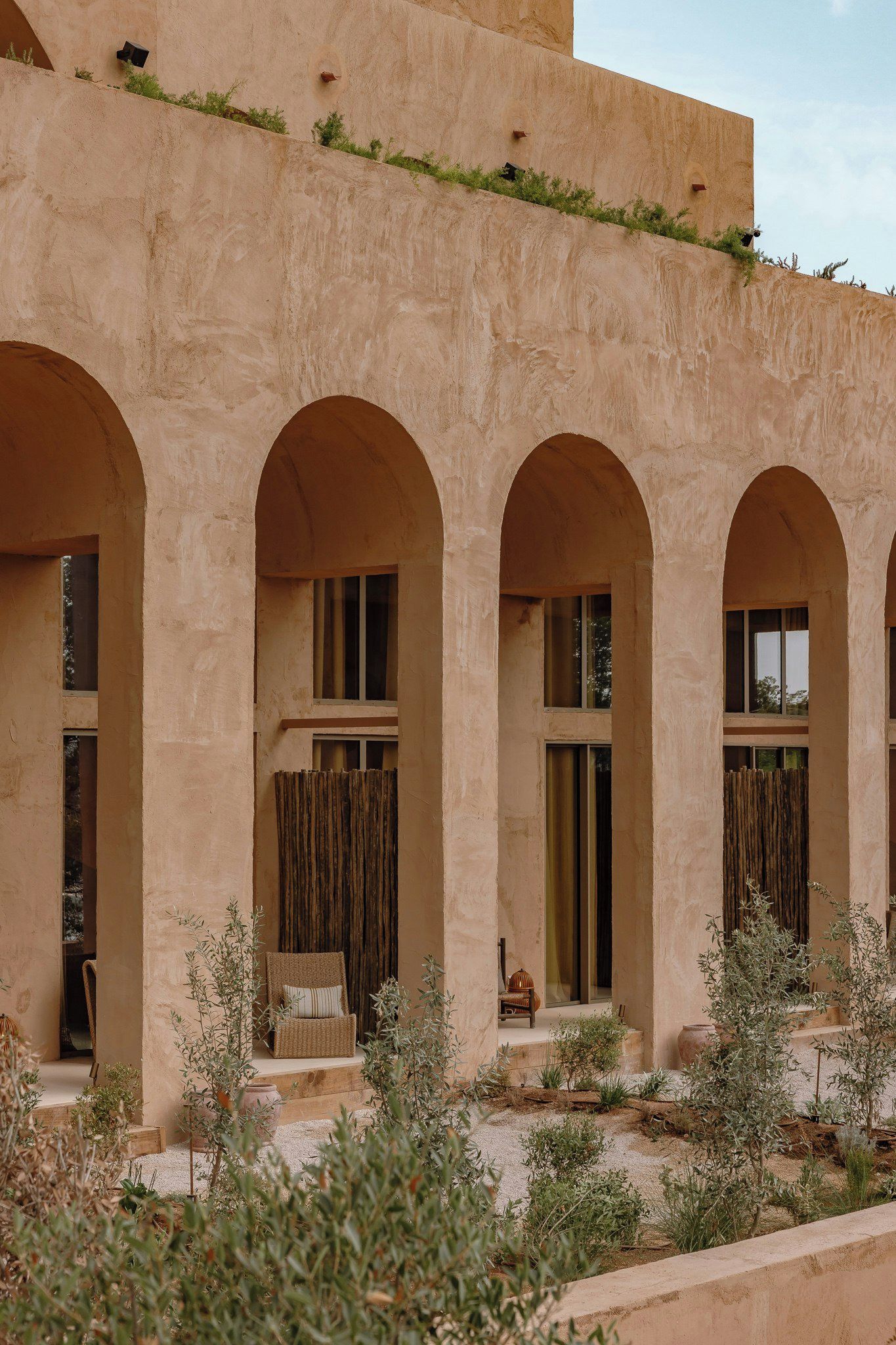 A building with multiple arched windows and a flat roof with vegetation.