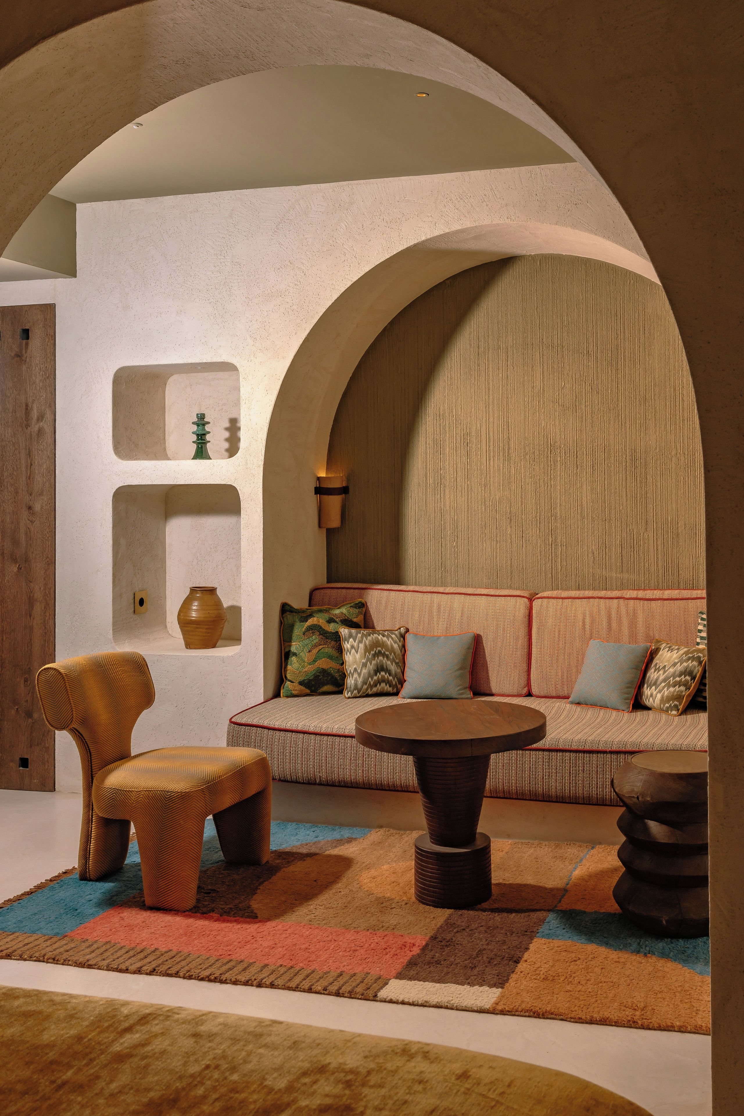 Ein gemütliches Interieur mit einer Couch, Sesseln, einem Couchtisch und einem gemusterten Teppich.
