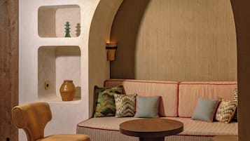 Ein gemütliches Interieur mit einer Couch, Sesseln, einem Couchtisch und einem gemusterten Teppich.