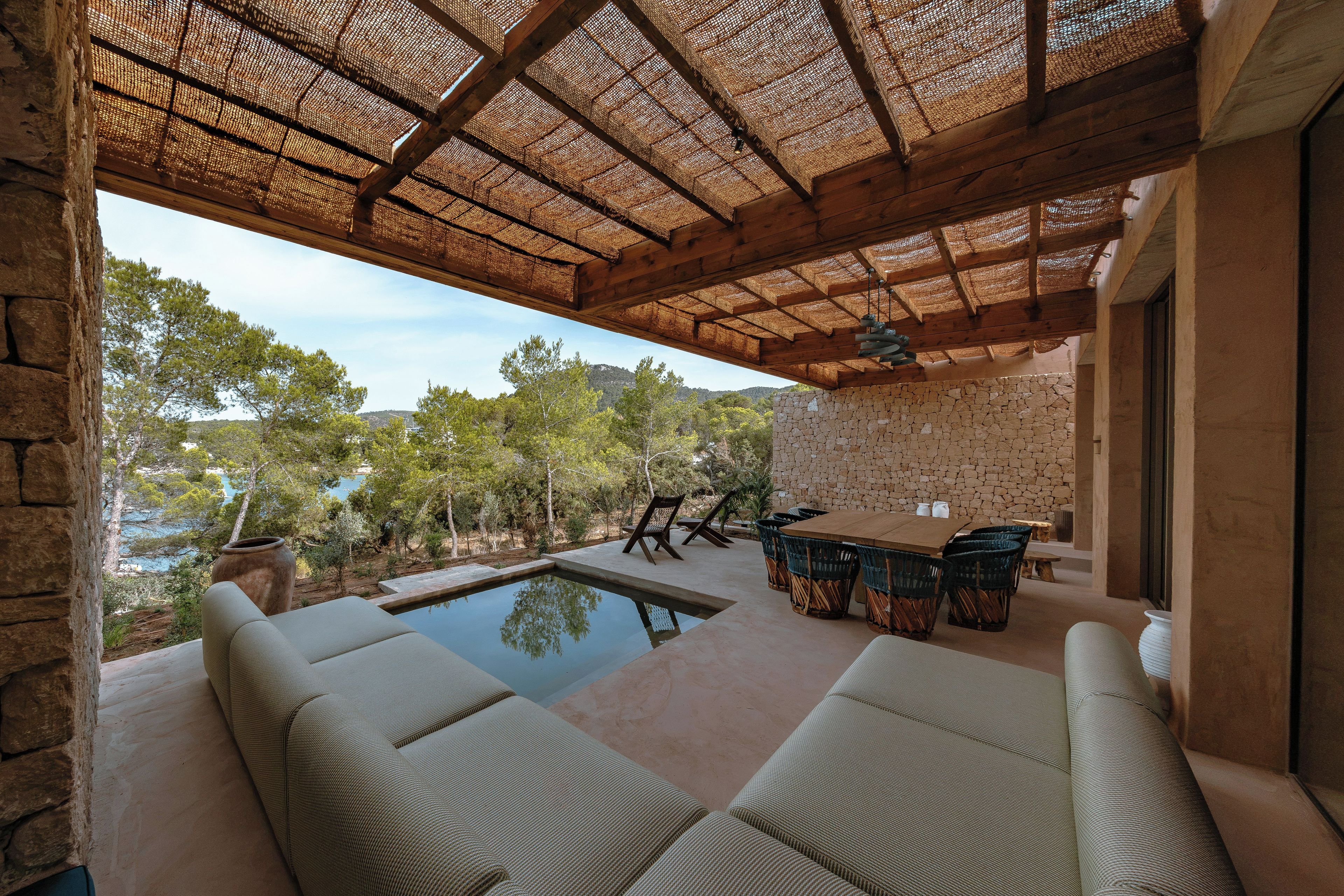An outdoor patio with a pool, seating area, and a stone wall.