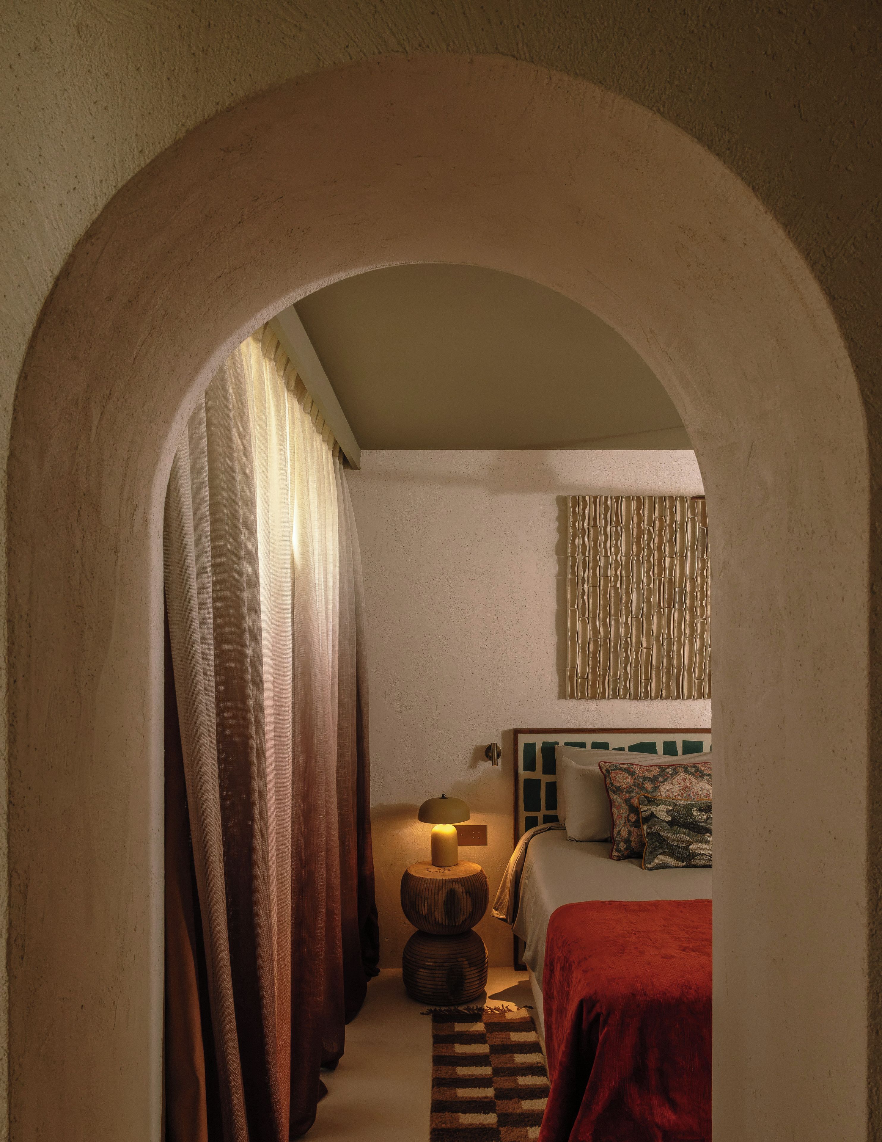 A room with a bed, a lamp, a rug, and curtains.