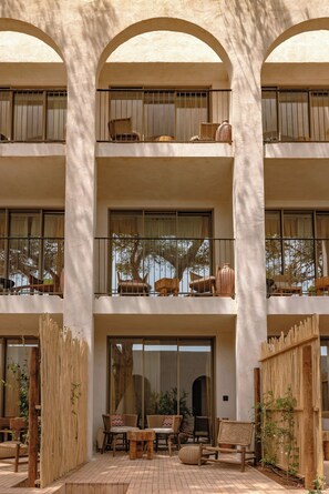 Un immeuble à plusieurs étages doté de balcons, de grandes fenêtres et d’espaces extérieurs aménagés pour s’asseoir.