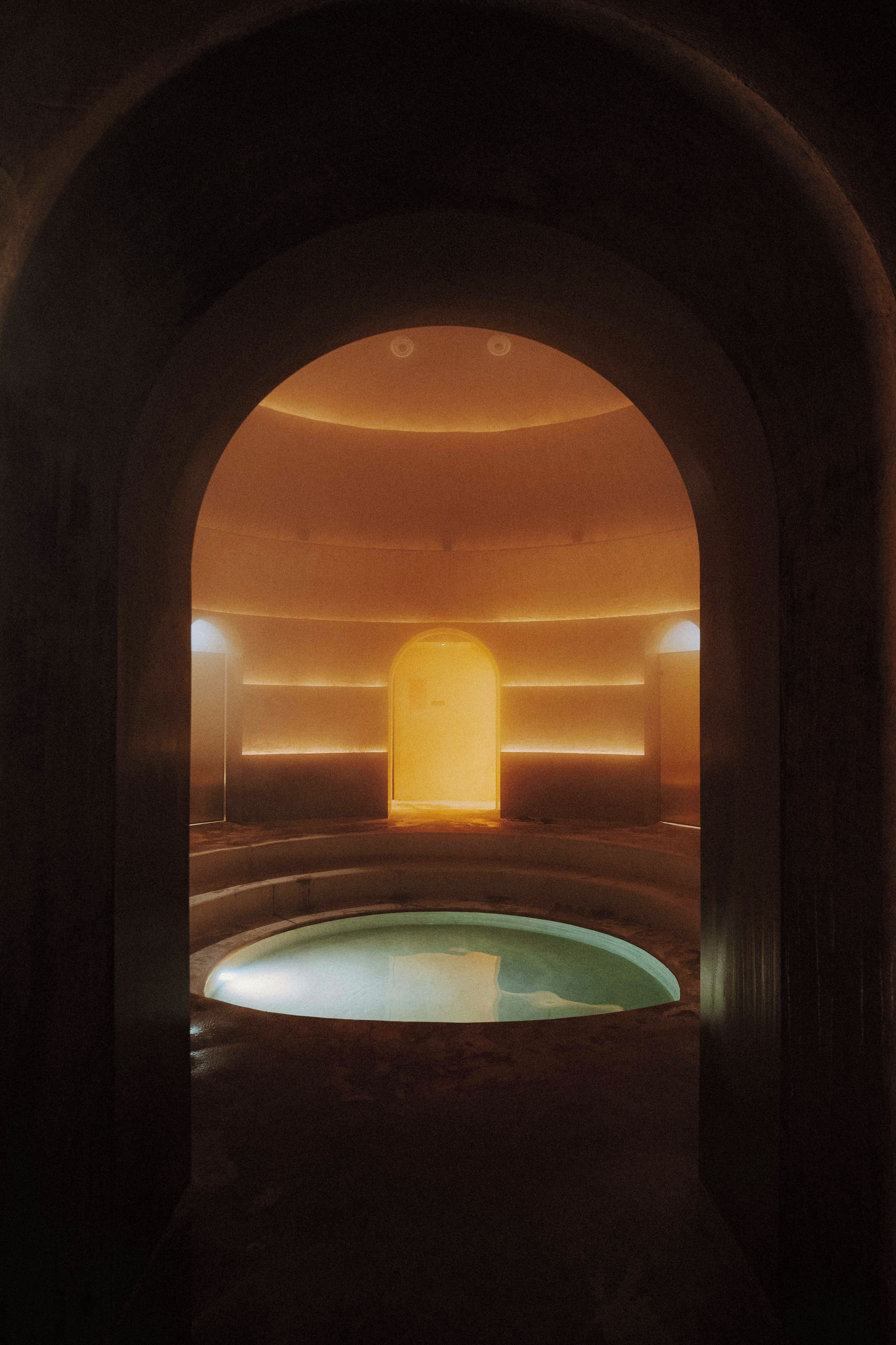 Una entrada arqueada que conduce a un interior tenuemente iluminado con una piscina.