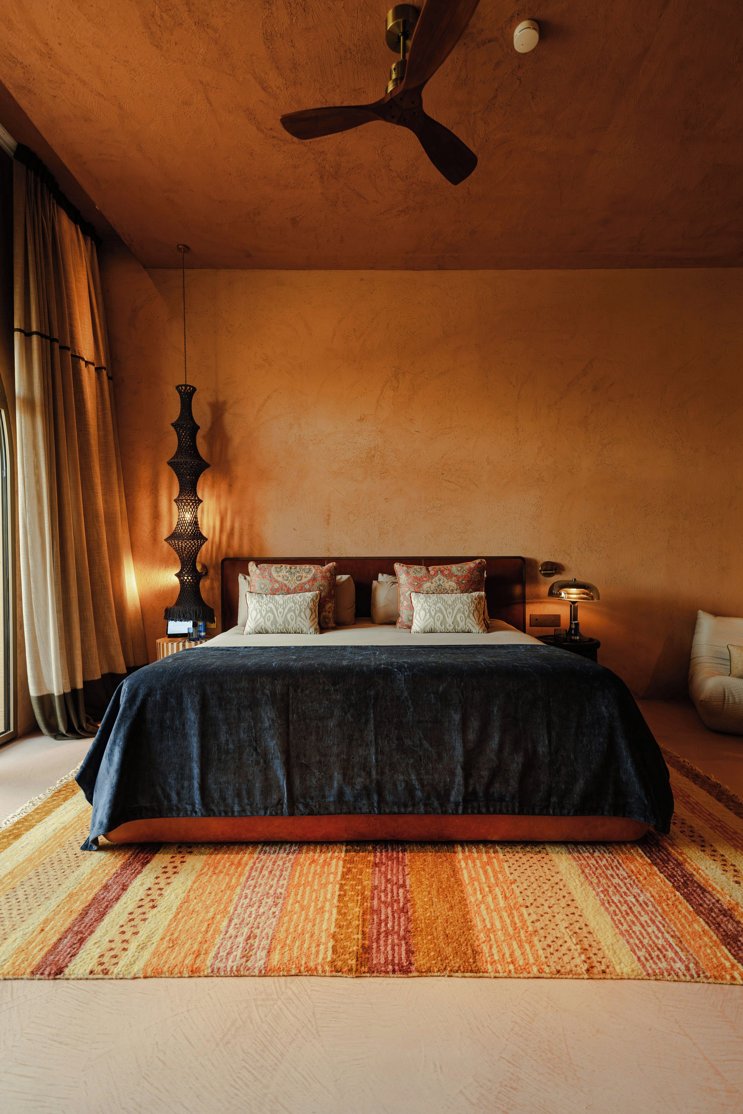 A bedroom with a bed, a ceiling fan, a nightstand, a lamp, and a window with curtains.