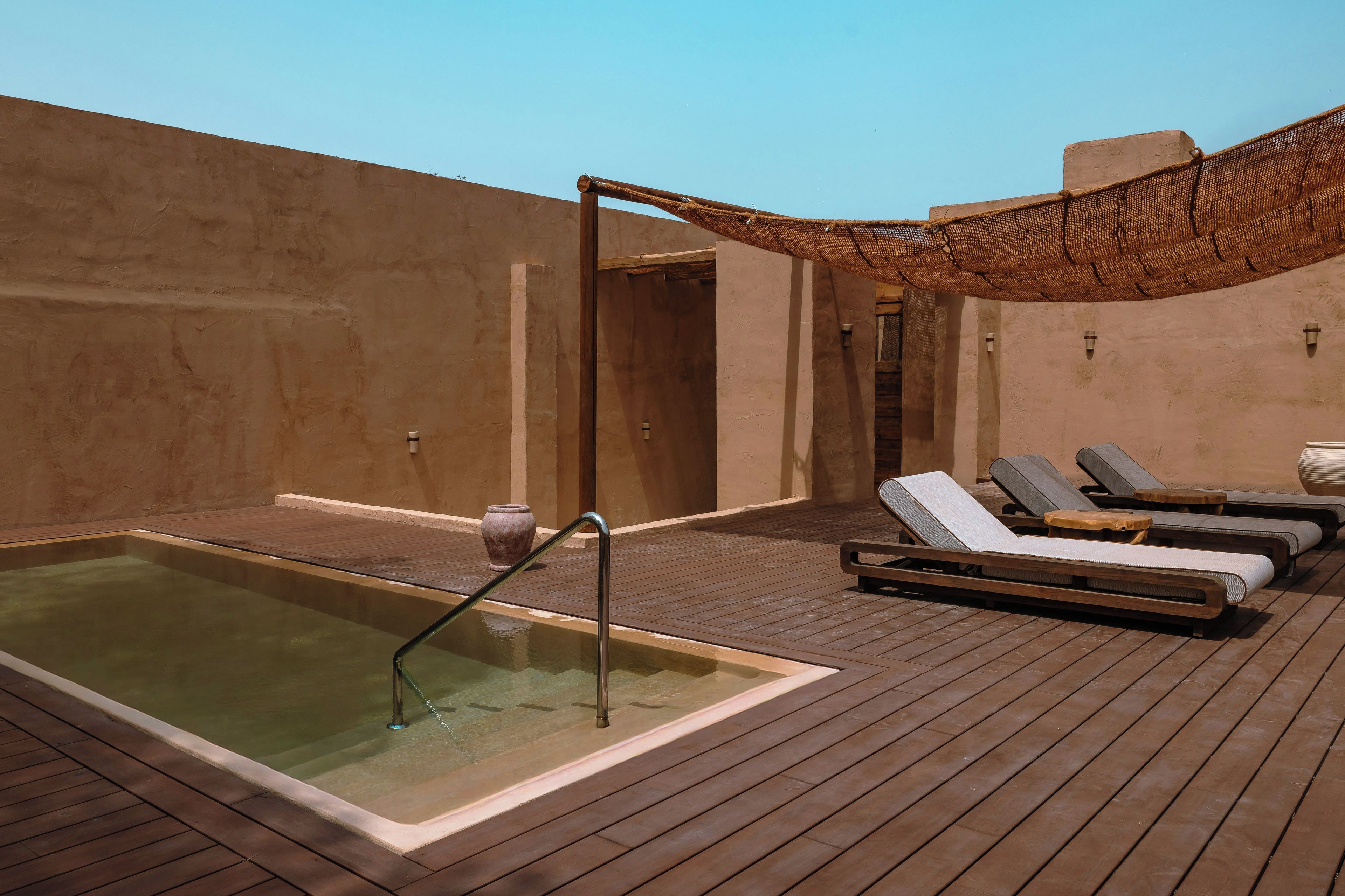 Eine Dachterrasse mit Whirlpool, Liegestühlen und einer Pergola.