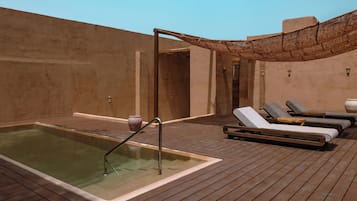 Eine Dachterrasse mit Whirlpool, Liegestühlen und einer Pergola.