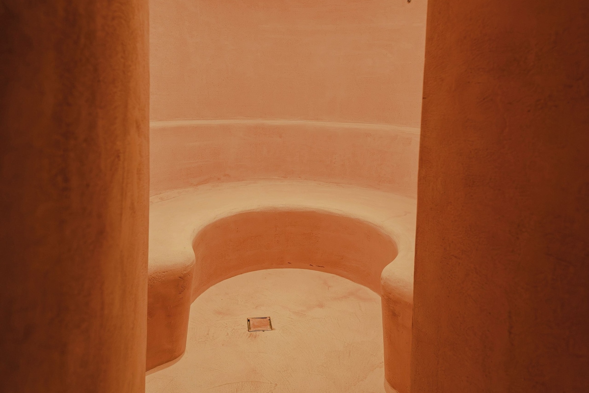 A corridor with a curved ceiling and a small square vent on the floor.