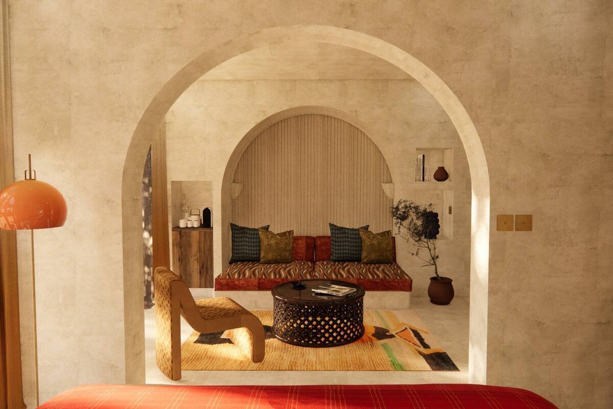 A cozy living room with a sofa, coffee table, and a chair, featuring an arched doorway and a hanging light fixture.