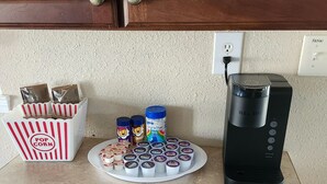 Uma bancada de cozinha com uma cafeteira, recipientes de pipoca e um prato de petiscos.