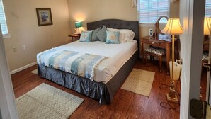 Quarto com uma cama grande, duas mesas de cabeceira, uma cadeira e uma escrivaninha.