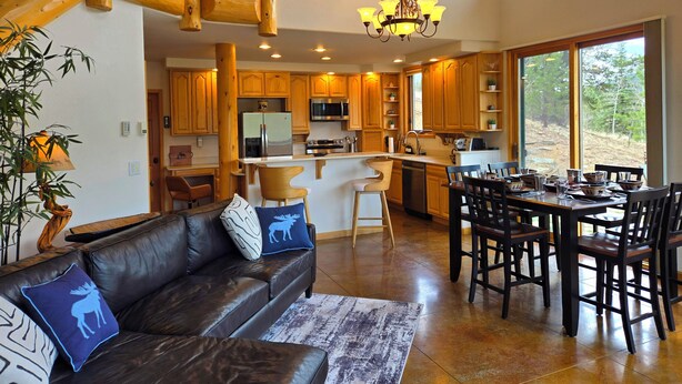 A spacious kitchen with wooden cabinets, a central island, and a dining area with chairs and a table.
