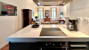 A modern kitchen with a central island, built-in oven, and a large range hood. - Le 100% Uzès, Right in the Historic Center (Uzès)