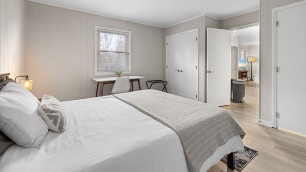 Une chambre avec un grand lit, un bureau avec une chaise et une fenêtre.