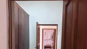 Un corridoio con pavimento piastrellato che conduce a una stanza con un letto e un comodino.