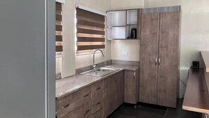 Una cucina compatta con forno a incasso, lavello e pensili in legno.