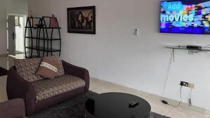 Un soggiorno con divano, tavolino, televisione a parete e quadro incorniciato.