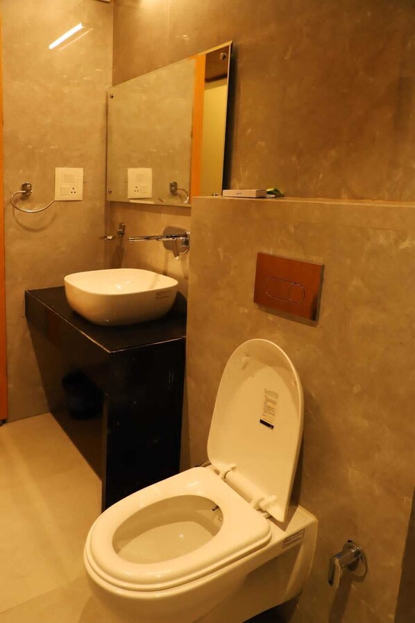 A bathroom with a white toilet, a black sink, and a mirror above the sink. - Ananda Castle (Vrindavan)