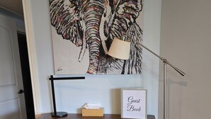 A wooden desk with a lamp, a framed sign, and a tissue box.