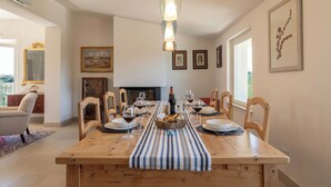 Un comedor con una mesa de madera dispuesta para cuatro personas, rodeada de sillas, un mantel a rayas y una lámpara colgante.