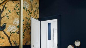 A room with a wooden floor, a white door leading to a bathroom, and a wall with a floral mural. - Hotel de Fouquet - Chambres d'h tes (Metz)