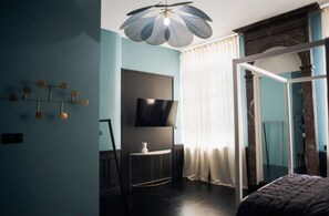 A modern bedroom with a bed, a TV, a small table, and a unique ceiling light fixture. - Hotel de Fouquet - Chambres d'h tes (Metz)