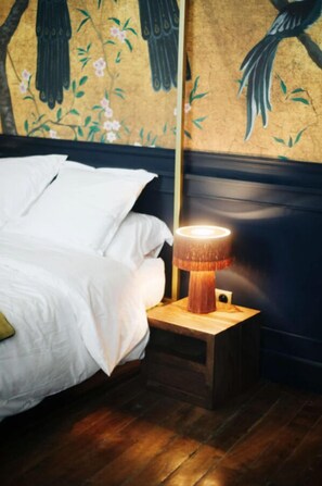 A bed with white linens, a wooden nightstand with a lamp, and a wall with a bird and floral mural. - Hotel de Fouquet - Chambres d'h tes (Metz)