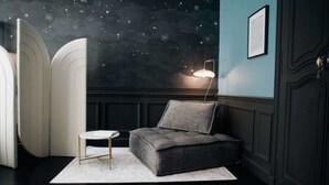 A cozy room with a dark blue wall, a starry night mural, a grey upholstered bench, a small white table, and a floor lamp. - Hotel de Fouquet - Chambres d'h tes (Metz)
