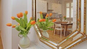 Espejo con marco dorado que refleja una habitación con una mesa de comedor, sillas y una zona de cocina.