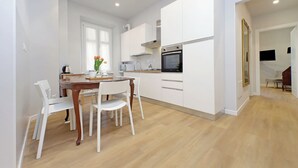 Una cocina moderna con armarios blancos, una mesa de comedor de madera y sillas blancas.