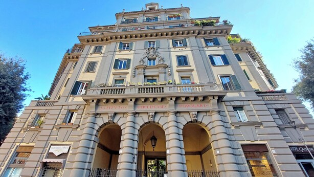Un edificio histórico con varios balcones, entradas en arco y un elemento decorativo central.