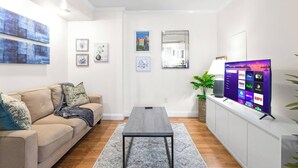 A modern living room with a sofa, a coffee table, a TV, and framed artwork on the walls. - Comfortable Apartment - 5 mins from UAB & Hospitals (Birmingham)