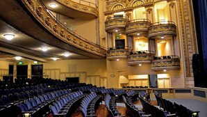 Un teatro imponente con balcones ricamente decorados y hileras de asientos.