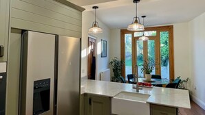A modern kitchen with stainless steel appliances, a marble countertop, and pendant lighting.