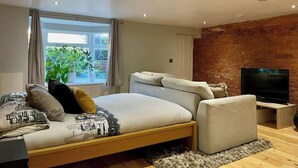 A modern living room with a sofa, a TV, and a brick wall.