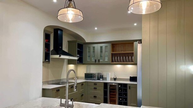 A modern kitchen with marble countertops, stainless steel appliances, and a wine rack.