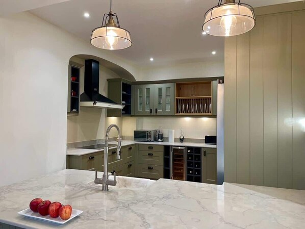 A modern kitchen with marble countertops, stainless steel appliances, and a wine rack.