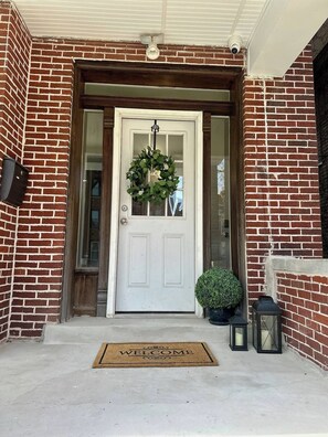 Welcome to a charming entrance with a decorative wreath, potted plant, and lanterns.