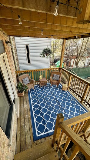 Relax on the deck with two comfortable chairs and a hanging plant, surrounded by a beautiful view.