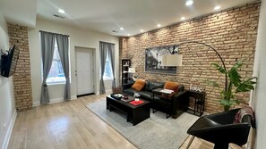 Relax in this stylish living room with a brick accent wall, black leather sofa, and a cozy coffee table.