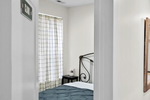 Cozy retreat with a single bed, bedside table, and window with a checkered curtain.