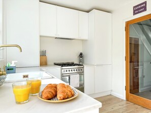 A modern kitchen with white cabinetry, a stove, and a sign indicating a chef's kitchen. - Modern 3 Bed Home - Pets Welcome + FREE Parking (Canterbury)