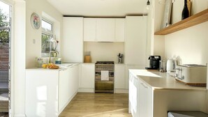 A compact kitchen with white cabinets, a stove, a coffee maker, and a toaster. - Modern 3 Bed Home - Pets Welcome + FREE Parking (Canterbury)