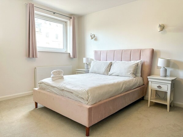 A bedroom with a bed, bedside tables, a window with curtains, and a wall-mounted lamp. - Modern 3 Bed Home - Pets Welcome + FREE Parking (Canterbury)