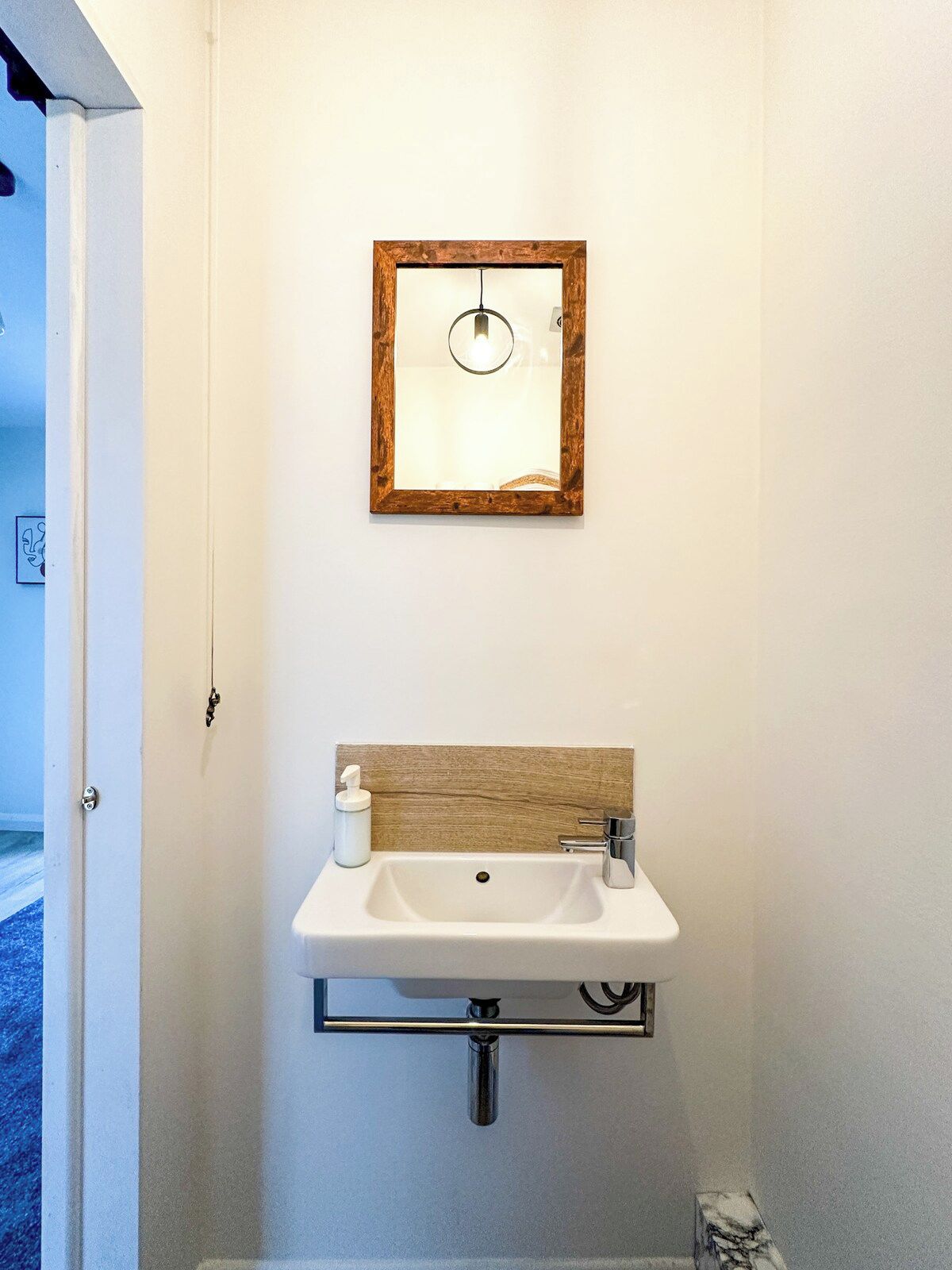 Ein Badezimmer mit einem weißen Waschbecken, einem Holzkopfstück und einem Spiegel mit Holzrahmen.