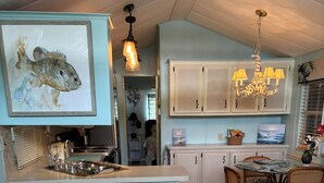 A cozy living room with a sofa, striped pillows, a dining area with a table and chairs, and a kitchen with cabinets and a chandelier. - Family fun amenities for all ages!Two bedroom ,sleeps 6, pet friendly ,relaxing. (Sarasota)