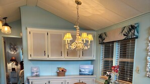 A kitchen with a dining table, chairs, and a chandelier. There are cabinets and a window with blinds. - Family fun amenities for all ages!Two bedroom ,sleeps 6, pet friendly ,relaxing. (Sarasota)