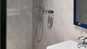 Ein Badezimmer mit Dusche, Waschbecken und Spiegel.